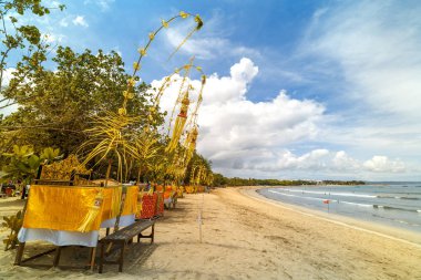 The penjor is a tall, curved bamboo pole decorated with coconut leaves with an offering at the base. Bali Indonesia. clipart