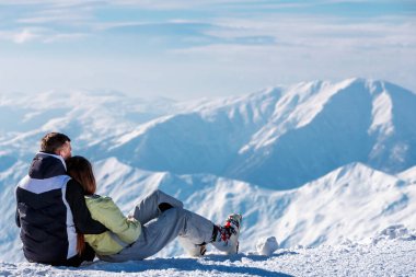 Kar üzerinde oturan ve peyzaj Dağı'nda zevk sarılma çift