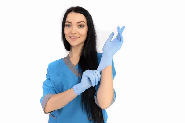 Kvinna läkare i blå uniform sätter på handskar Royaltyfria Stockfoton