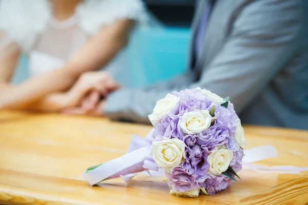 Bouquet de mariée sur le fond des jeunes mariés — Photo
