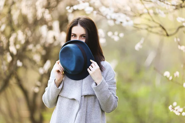 Menina em um chapéu verde em um jardim florescente — Fotografia de Stock