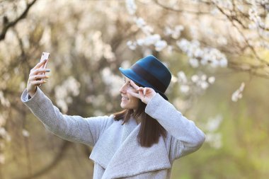 Telefon ile çiçek açan bir bahçede poz güzel kız