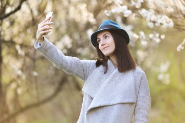 Telefon ile çiçek açan bir bahçede poz güzel kız