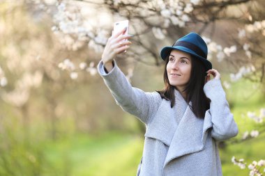 Telefon ile çiçek açan bir bahçede poz güzel kız