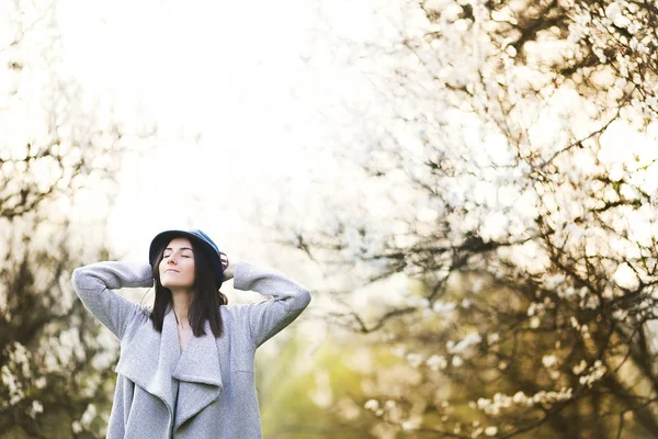 Menina em um chapéu verde em um jardim florescente — Fotografia de Stock