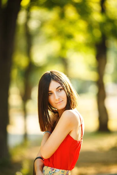 Красивая женщина в красной блузке гуляет по парку — стоковое фото
