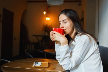 Kırmızı fincan kahve güzel bir gülümseyen kız elinde