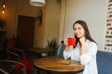 Kırmızı fincan kahve güzel bir gülümseyen kız elinde