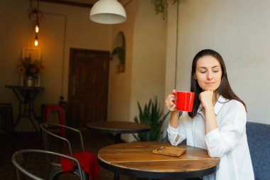 Kırmızı fincan kahve güzel bir gülümseyen kız elinde