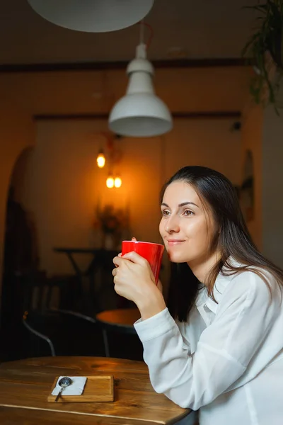 Красная чашка кофе в руках красивой улыбающейся девушки — стоковое фото