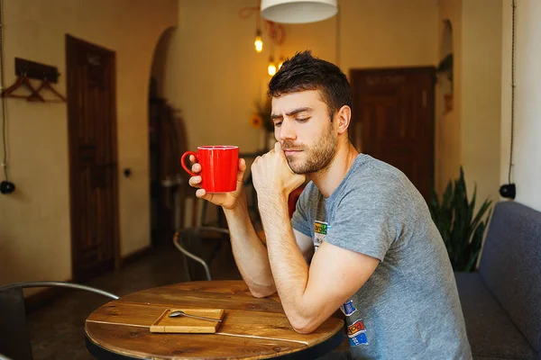 Человек с красной чашкой кофе в руке — стоковое фото