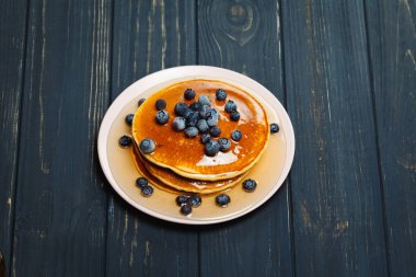 Bal ve ahşap masa üzerinde yaban mersini ile Pancakes