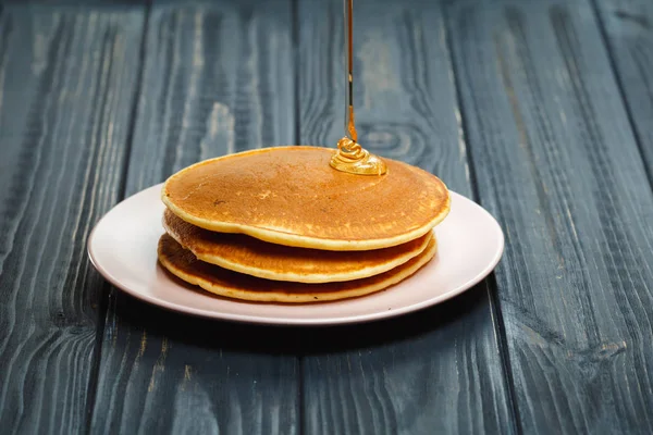 Stapel von Pfannkuchen mit Honig auf Holz Hintergrund — Stockfoto