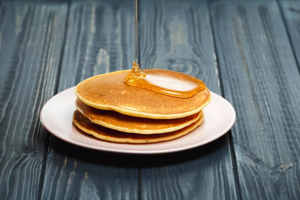 Stapel von Pfannkuchen mit Honig auf Holz Hintergrund — Stockfoto