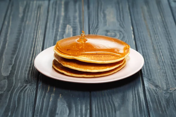 Stapel von Pfannkuchen mit Honig auf Holz Hintergrund — Stockfoto