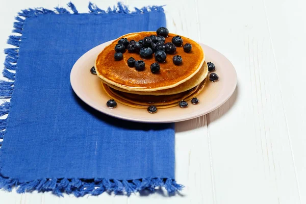 Pancakes with honey and blueberries on a blue napkin — Stock Photo, Image