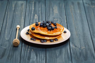 Bal ve ahşap masa üzerinde yaban mersini ile Pancakes