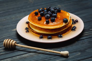 Bal ve ahşap masa üzerinde yaban mersini ile Pancakes