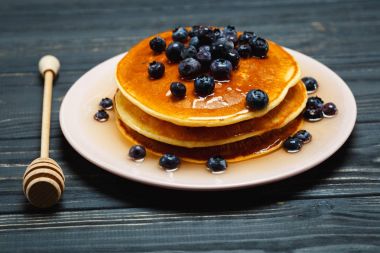 Bal ve ahşap masa üzerinde yaban mersini ile Pancakes