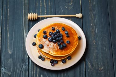 Bal ve ahşap masa üzerinde yaban mersini ile Pancakes