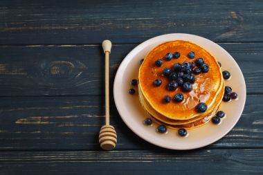 Bal ve ahşap masa üzerinde yaban mersini ile Pancakes