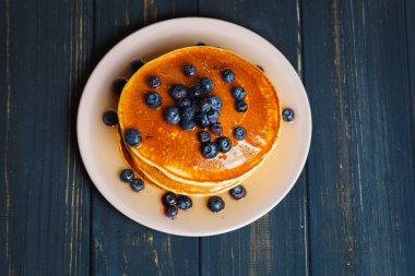 Bal ve ahşap masa üzerinde yaban mersini ile Pancakes