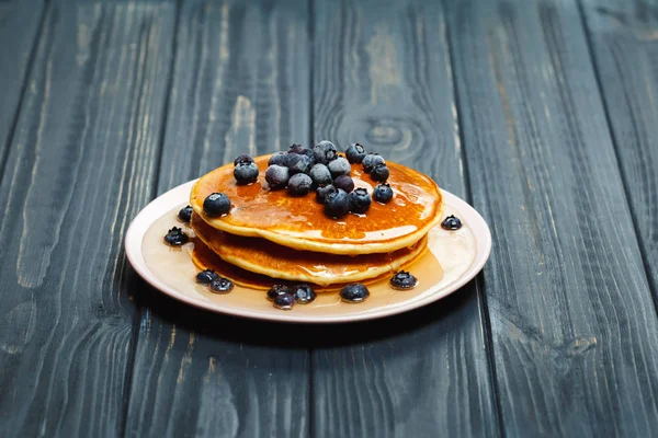 Bal ve ahşap masa üzerinde yaban mersini ile Pancakes