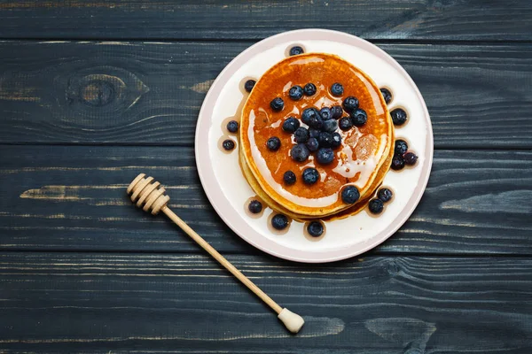 Bal ve ahşap masa üzerinde yaban mersini ile Pancakes