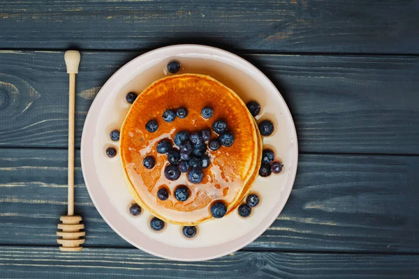 Pancake dengan madu dan blueberry di atas meja kayu — Stok Foto