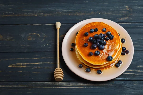 Bal ve ahşap masa üzerinde yaban mersini ile Pancakes