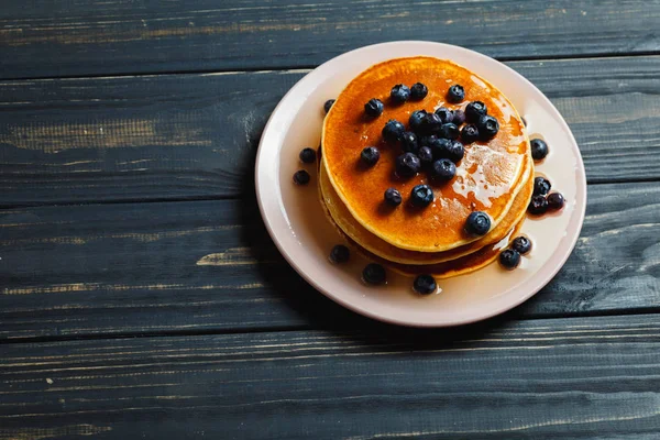 Pancake dengan madu dan blueberry di atas meja kayu — Stok Foto