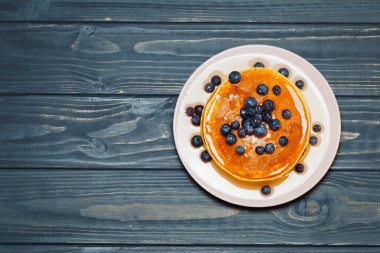 Bal ve ahşap masa üzerinde yaban mersini ile Pancakes