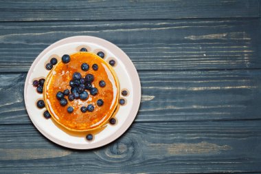 Bal ve ahşap masa üzerinde yaban mersini ile Pancakes