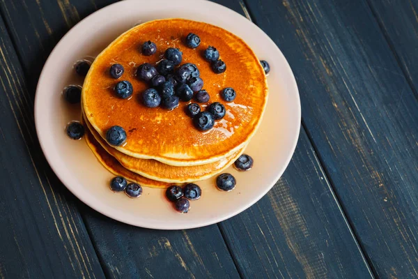 Pancake dengan madu dan blueberry di atas meja kayu — Stok Foto