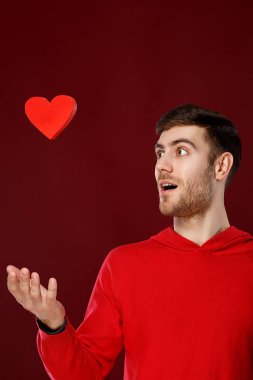 Sevgililer günü onun elinde kırmızı bir kalp ile yakışıklı delikanlı