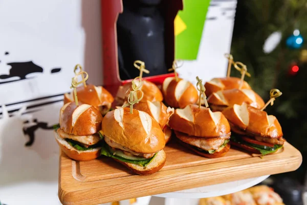 Tahta kesme tahtasında servis edilen küçük tavuk burgerleri.