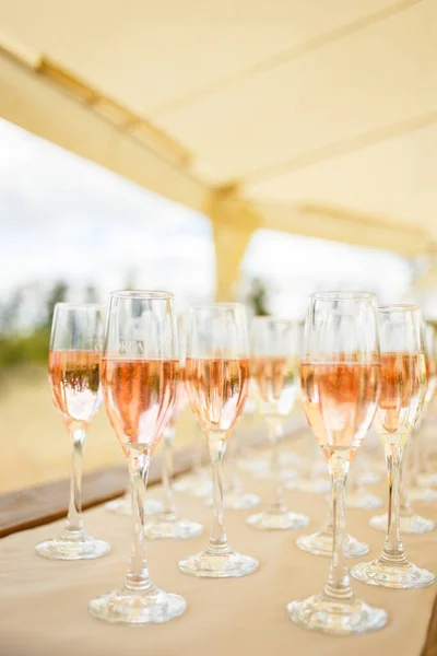 Elegant glasses with champagne standing in a row on serving table during party or celebration