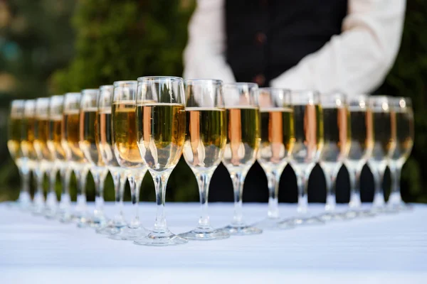 the waiter pours champagne in glasses on the street - wedding catering