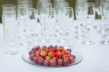 Şarap için çilek ve kırmızı üzüm. Arka planda şarap kadehi.