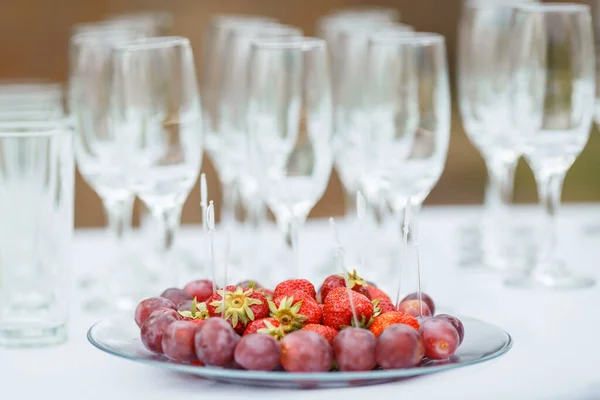 Strawberries and red grapes for wine. Wineglass on the background.