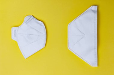 Sarı arka planda iki çeşit koruyucu yüz maskesi. Koronavirüs 2019-nCoV yayılımında önlem olarak koruyucu maskeler..