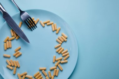 Tabakta çatal ve mavi arka planda bıçak olan haplar.