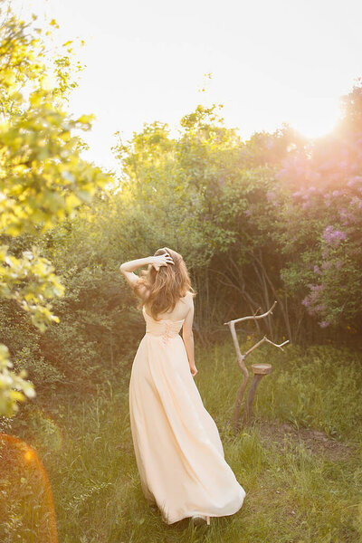 Beautiful girl in a vintage dress in spring lilac garden.