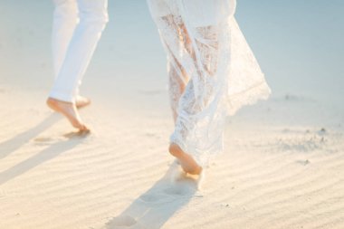 Aşıklar beyaz çölde kumda yalın ayak yürür. Çölde aşk, yeni evliler..