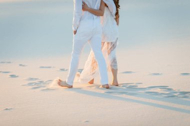 Aşıklar beyaz çölde kumda yalın ayak yürür. Çölde aşk, yeni evliler..