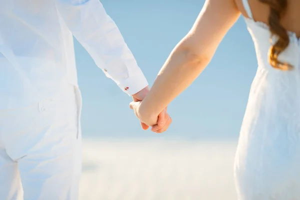 幸せなカップルの手を取り合って白い砂漠を歩く — ストック写真