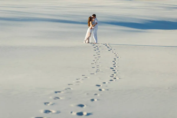 Newlyweds walk barefoot on the sand in the white desert. Love in the desert newlyweds.