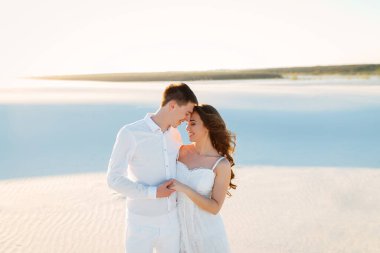 Yeni evliler romantik bir balayı gezisi sırasında beyaz bir çölde sarılıyorlar..