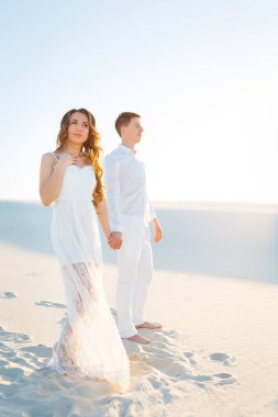 Yeni evliler, beyaz çölde kumların üzerinde yalınayak yürürler. Çölde aşk, yeni evliler..