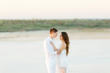 Romantik bir balayı gezisi sırasında beyaz bir çölde sarılan genç çift..